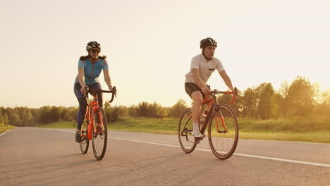 Entrenamiento-Duro.triatleta-Dos-Ciclistas-Entrenando-En-Bicicleta-De-Carretera.-Dos-Ciclistas-Montando-En-Bicicleta-De-Carretera-En-El-Parque-De-La-Ciudad-Y-Preparándose-Para-El-Triatlón.-Entrenamiento-Intensivo-De-Atletas-En-Forma-Dos-Hombres-Y-Mujeres-En-Bicicleta-Antes-De-La-Competencia-De-Triatlón.